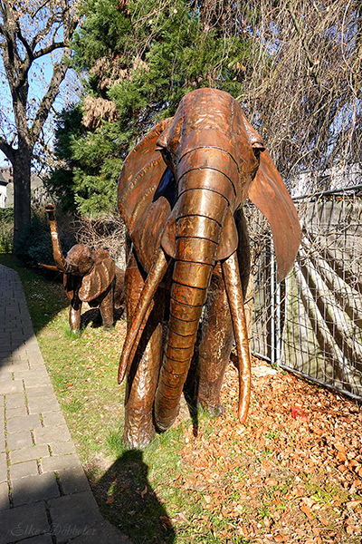 Eine große und eine kleine Elefantenskulptur aus Metallplatten stehen im Freien auf einer Wiese.